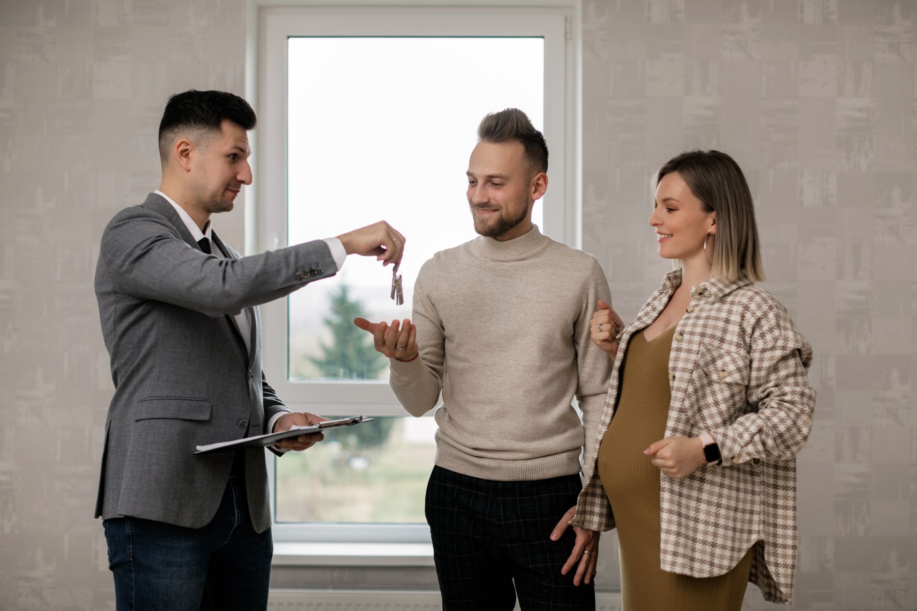 A real estate agent handing keys to a couple in their new home